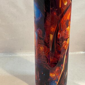 May include: A stainless steel tumbler with a colorful abstract design featuring shades of orange, blue, and yellow. The design appears to be a close-up of a complex machine or engine.