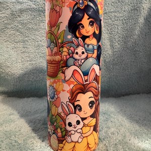 May include: A white ceramic mug with a black handle and the text "But First, Coffee" in a bold, black font. The mug is set against a blurred background, suggesting a cosy setting.