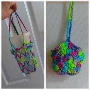 Könnte beinhalten: Ein gehäkelter Becherhalter in Netzoptik, der einen Starbucks-Becher mit einem grünen Strohhalm hält. Der Halter ist aus neongrüner, rosa, blauer und grauer Wolle gefertigt. Ein passendes gehäkeltes Blumenornament ist ebenfalls abgebildet.