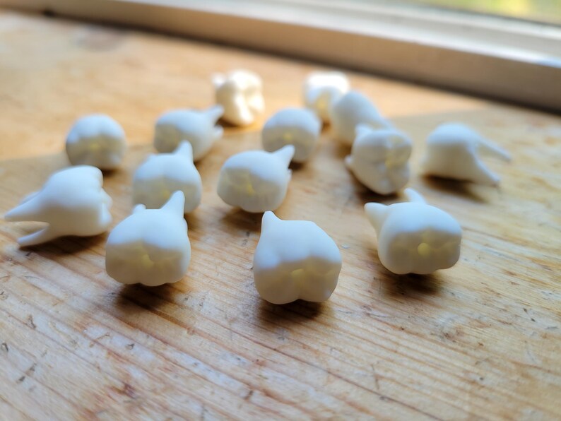 Pu&ograve; includere: Un insieme di denti di plastica bianca, che ricordano un set di denti da latte, sono sparsi su una superficie di legno.