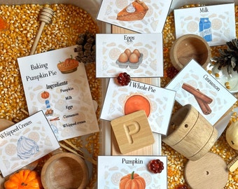 Könnte beinhalten: Ein Sinnesbecken gefüllt mit Maiskörnern, Holzschalen, einem Holzeimer, einem Holznudelholz und einem Holzbuchstaben P. Es gibt auch Karten mit Bildern und Text, darunter "Baking Pumpkin Pie", "Ingredients", "Pumpkin", "Milk", "Eggs", "Cinnamon", "Whipped cream", "1 Slice of Pie", "1 Whole Pie" und "Pumpkin".