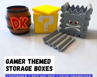 May include: Gamer-themed storage boxes in the image include a brown barrel with "DK" lettering, a yellow question mark box, and a gray Thwomp-shaped container. The boxes are designed as desk organizers and pen holders.
