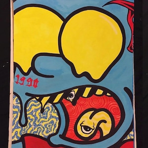 May include: A colorful illustration on paper featuring a blue character with large yellow eyes, a wide open mouth revealing a red interior with a swirling pattern, a yellow tongue with an eye, and the red text 1990 on the left side.