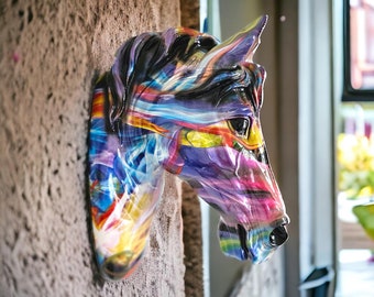 May include: A colorful abstract horse head sculpture with a purple, pink, blue, yellow, and black paint design. The sculpture is mounted on a wall.