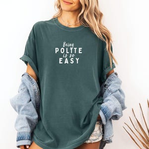 May include: A teal blue t-shirt with the text "Being Polite is so Easy" in white lettering.