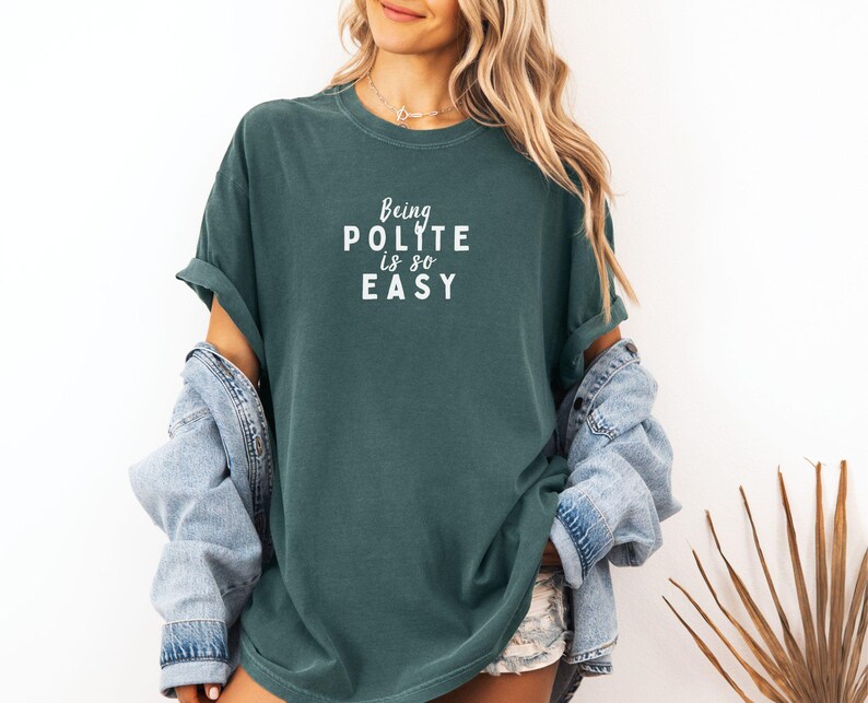 May include: A teal blue t-shirt with the text "Being Polite is so Easy" in white lettering.