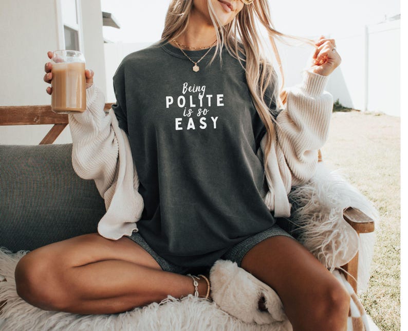May include: A dark gray long-sleeved shirt with the text "Being Polite is so Easy" printed in white on the front.