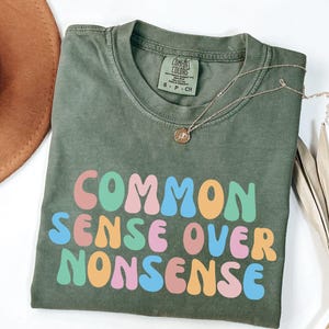 May include: A green t-shirt with the text "COMMON SENSE OVER NONSENSE" in rainbow colored letters.