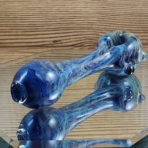 May include: A blue glass pipe with white and yellow swirls. The pipe has a round bowl and a long, curved stem.