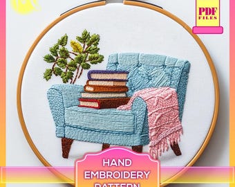 以下が含まれることがあります： 青いアームチェアに本を積み重ね、ピンクの毛布をかけた手刺繍のパターン。パターンは木製の刺繍枠に入っています。枠の下に「HAND EMBROIDERY PATTERN」の文字があります。