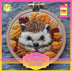 May include: Embroidered design of a hedgehog surrounded by autumn leaves in a wooden embroidery hoop. The design is titled "Hand Embroidery Pattern".