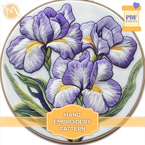 Può includere: Modello di ricamo a mano con tre fiori di iris viola e bianchi con centri gialli, circondati da foglie verdi. Il modello è in un cerchio e il testo "HAND EMBROIDERY PATTERN" è sotto i fiori.