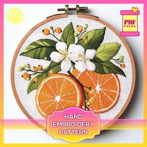 Könnte beinhalten: Ein Stickmuster für Handarbeiten mit einer weißen Blüte mit grünen Blättern und zwei Orangenscheiben. Das Muster ist in einem hölzernen Stickrahmen dargestellt. Der Text "HAND EMBROIDERY PATTERN" ist unter dem Rahmen abgebildet.
