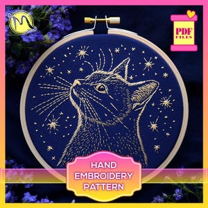 May include: A hand embroidery pattern featuring a cat looking up at a starry night sky. The cat is outlined in gold thread on a dark blue fabric. The pattern is available as a PDF download.