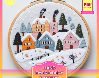May include: A hand embroidery pattern featuring a winter village scene with colorful houses, trees, and snow. The pattern is in a hoop and includes the text "HAND EMBROIDERY PATTERN".