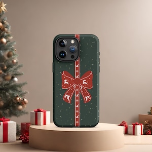 May include: A green phone case with a red bow and white snowflakes. The case has a festive Christmas design.