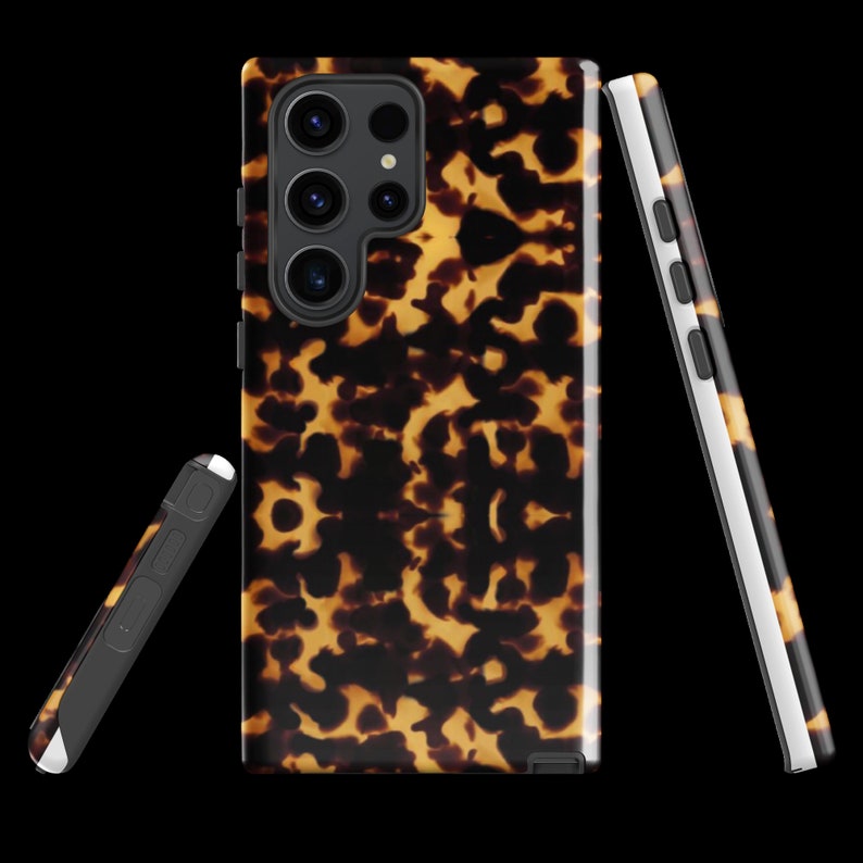 Puede incluir: Una funda para tel&eacute;fono con estampado de caparaz&oacute;n de tortuga con una protuberancia de c&aacute;mara negra y tres lentes. La funda se muestra desde el frente y el lateral.