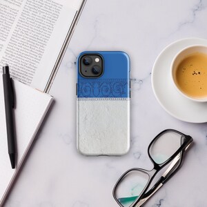 May include: A blue and white phone case with a decorative design. The case has a textured white bottom half and a blue top half with a decorative design. The case has a camera lens cutout on the back.