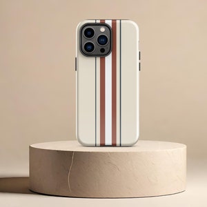 May include: A white iPhone case with a brown and white striped design. The case is on a beige pedestal.