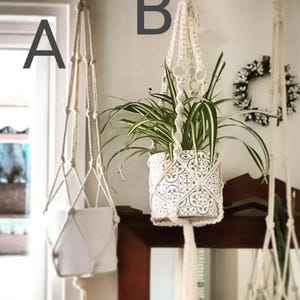 May include: Two macrame plant hangers made with white rope and tassels. The hanger on the left is empty, while the hanger on the right holds a potted plant with green leaves.