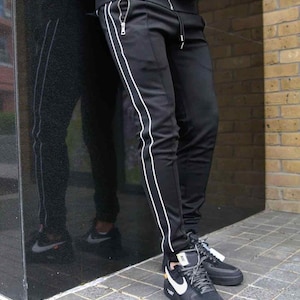 Pantalones deportivos para hombre con rayas laterales, corte ajustado y bolsillos con cremallera, estilo urbano informal, color negro/gris