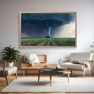 May include: A framed photograph of a tornado in a field. The tornado is a dark grey color and is surrounded by a dark grey sky. The field is green and there are trees in the distance.