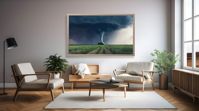 May include: A framed photograph of a tornado in a field. The tornado is a dark grey color and is surrounded by a dark grey sky. The field is green and there are trees in the distance.