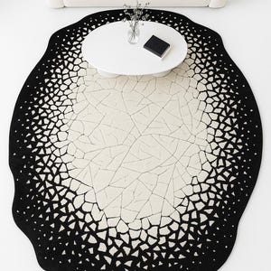 Top view of modern black and ivory cracked eclipse rug laid flat showing abstract circular design.