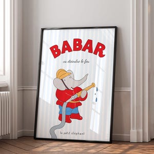 May include: Framed print featuring Babar the elephant in a red firefighter's uniform, holding a hose. The text "BABAR va éteindre le feu" is in red above the illustration, with "le petit éléphant" below. The background has vertical blue and white stripes.