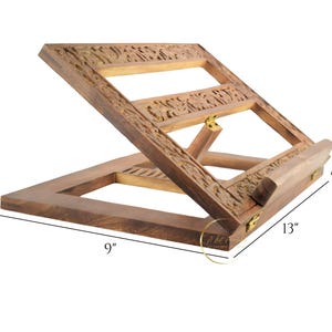 May include: A wooden book stand with intricate carvings. It measures 9 inches wide, 13 inches long, and 1.5 inches high.