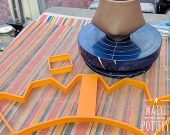 Può includere: Un vaso di ceramica marrone è su un tornio blu. Un tagliapasta a forma di corona arancione e un tagliapasta quadrato sono su una superficie a strisce. Il testo "Waiyi Pottery" è incluso.