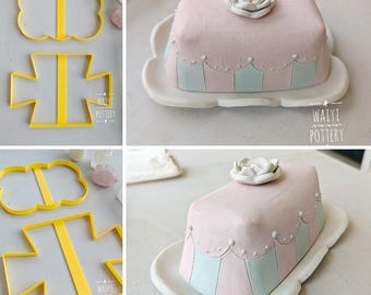Può includere: Un collage di oggetti in ceramica fatti a mano. Include formine gialle a forma di farfalla e croce. Inoltre, una burriera rosa e blu con un fiore bianco, su un piatto bianco. La ceramica è di Waiyi Pottery.