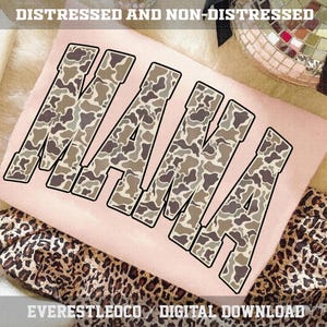 May include: A light pink t-shirt with the word "MAMA" in large, camouflage-patterned letters. The text is outlined in black. The words "DISTRESSED AND NON-DISTRESSED" are at the top. The bottom of the image shows a leopard print fabric.