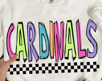 Può includere: Felpa bianca con la scritta "CARDINALS" in grandi lettere colorate. Le lettere sono bordate di nero e hanno un effetto 3D con tonalità rosa, verde, blu, arancione e viola. Un motivo a scacchi in bianco e nero è in basso.