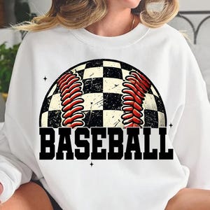 Pu&ograve; includere: Felpa bianca con una grafica di baseball a scacchi bianco e nero e la parola "BASEBALL" in lettere nere.