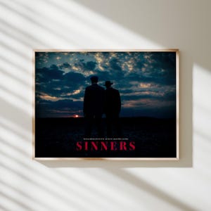 May include: A framed rectangular print featuring a silhouette of two figures in hats standing in a dark field against a sunset sky. The text reads: You keep dancing with the devil... one day he's gonna follow you home. SINNERS in bold red letters.