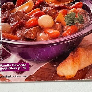 May include: A close-up of a cookbook page featuring a hearty beef stew. The stew is in a purple bowl and includes chunks of beef, carrots, and onions. A piece of bread is on the side. The text "Family Favorite Beef Stew p. 76" is visible.