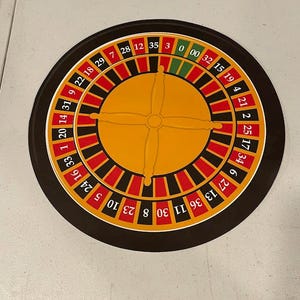 May include: A circular roulette wheel with a black outer ring, red and black number slots, and a yellow center. The numbers are clearly visible, and the wheel is designed for casino games.