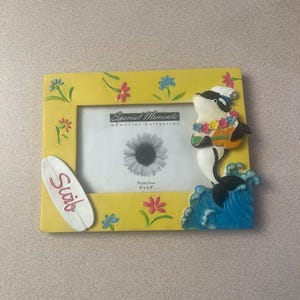 May include: Yellow picture frame with a decorative orca whale, surfboard, and floral accents. The frame has the text "Special Moments Memories Collection" and is sized for a 5" x 3.5" photo.