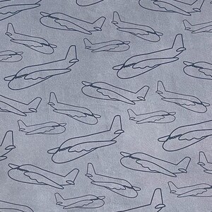 May include: A repeating pattern of dark blue airplane outlines on a light gray background. The airplanes are depicted in a simple line drawing style, with a focus on the overall shape and form of the aircraft. The design is evenly spaced across the surface.