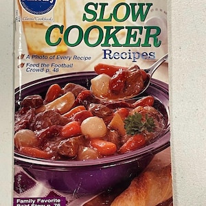 May include: A Pillsbury "Slow Cooker Recipes" cookbook cover. The cover features a photo of beef stew with carrots and onions in a purple bowl. Text includes "A Photo of Every Recipe" and "Family Favorite Beef Stew p. 76".