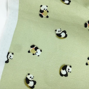 Peut inclure: Tissu vert clair avec un motif répété de petites illustrations d'ours pandas noirs, blancs et jaunes. Le tissu a une texture douce et une bordure blanche sur le côté gauche.