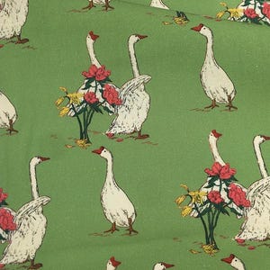 May include: Green fabric with a repeating pattern of white geese with red beaks and floral arrangements. The geese are interspersed with bouquets of red flowers and yellow accents. The text "SANMU IMPRESSION" is printed vertically on the left side.
