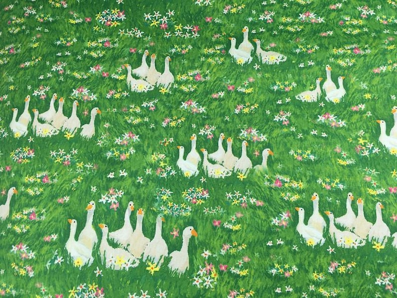May include: A green fabric with a repeating pattern of white geese and colorful flowers. The geese are clustered in groups, and the flowers are scattered throughout the green background.