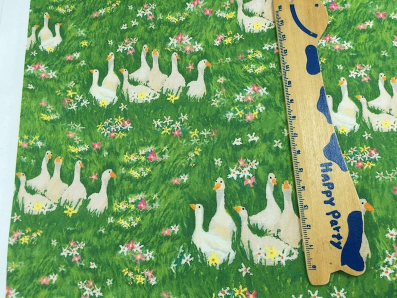 May include: Fabric with a green background featuring white geese and colorful flowers. A wooden ruler with blue accents and the words "Happy Party" is on the right side of the image.