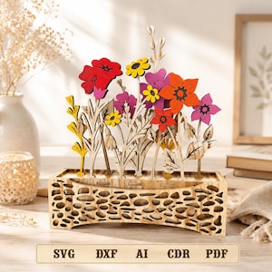 May include: A wooden decorative display featuring a rectangular base with a laser-cut pebble pattern, holding an arrangement of flat, colorful wooden flowers in shades of red, orange, yellow, and purple. Text at the bottom reads SVG DXF AI CDR PDF.