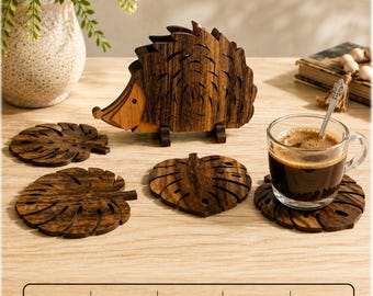 Puede incluir: Un soporte de madera marrón oscuro con forma de erizo que contiene varios posavasos de madera marrón oscuro con forma de hojas de monstera. Un posavasos está bajo una taza de cristal con café negro. El texto SVG, DXF, AI, CDR, PDF es visible.