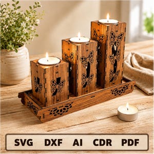 May include: Three rectangular wooden candle holders of varying heights, each featuring laser-cut butterfly silhouettes, arranged on a matching rectangular wooden tray. Each holder contains a white tea light candle. Text reads: SVG DXF AI CDR PDF.