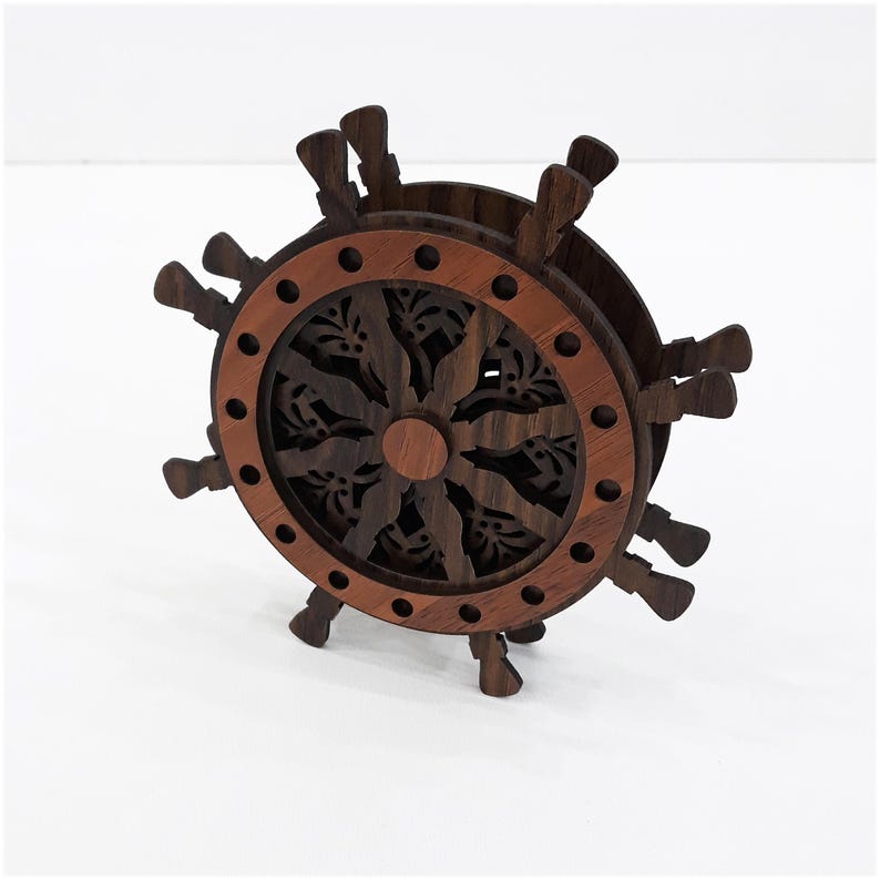 May include: A dark brown wooden ship wheel shaped holder featuring a circular frame with a lighter brown outer ring and intricate cut-out patterns in the center. The structure includes multiple protruding handles around the perimeter.