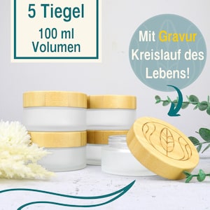 May include: Five clear glass jars with bamboo lids. Each jar has a capacity of 100 ml. The lids have a leaf design engraved on them. The text "Mit Gravur Kreislauf des Lebens!" is visible in the image.